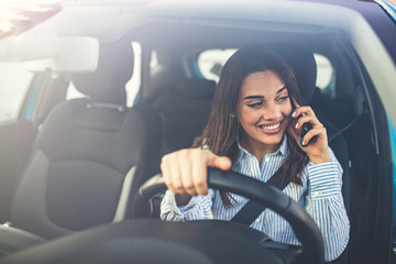 Woman In Car Talking On Mobile Phone Whilst Driving. Attractive woman uses smart phone while driving. Beautiful female Driver talking on the Phone.