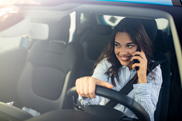 Young woman driving his car and talking on the phone. Woman Talking on Mobile while Driving. Businesswoman multitasking while driving, drinking coffee and talking on the phone