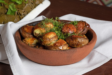 vegan food grilled mushrooms with cheese and herbs in a ceramic bowl on a light napkin
