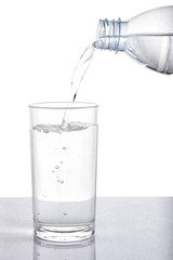 Pouring water from bottle into glass on white background with clipping path.