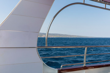 Beautiful view over the adriatic sea water shot at the deck on board of a boat with white and metal details. The waves in the water, view and the white and blue colors creating the feeling of freedom.