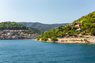 Fototapeta na wymiar Pucisca town at Brac in Croatia, view from the sea on a sunny day in the summer. The port with it’s famous limestone from the island. Beautiful landscape, white stone creating a beautiful scenery