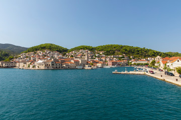 Fototapeta na wymiar Pucisca town at Brac in Croatia, view from the sea on a sunny day in the summer. The port with it’s famous limestone from the island. Small idyllic place, village in Dalmatia.