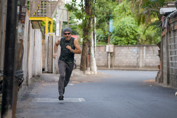 outdoors urban jogging workout - young attractive and happy man running in the city enjoying fitness and sport in healthy lifestyle concept
