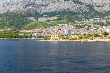 Fototapeta na wymiar Makarska in Dalmatia, Croatia. View from the sea on a sunny day in the summer. A famous place with beaches and the Biokovo mountain. Holiday destination at the Mediterranean coast. Relaxing