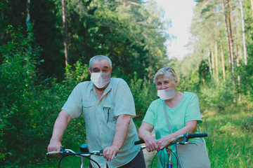 active senior couple maintaining social distancing on bike ride in nature