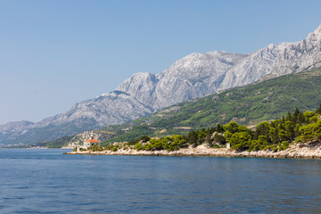 Makarska in Dalmatia, Croatia. View from the sea on a sunny day in the summer and a blue sky. A famous place with beaches and the Biokovo moutain. Holiday destination, Mediterranean coast