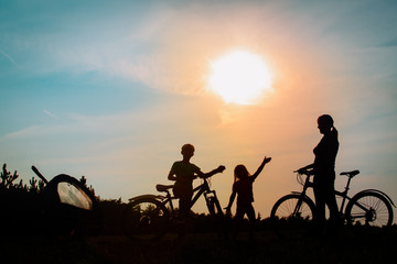 Fototapeta na wymiar Happy mother with kids biking at sunset, family exercise in nature