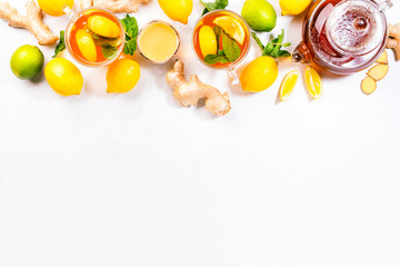 Healing black herbal tea with ginger, honey, lemon and mint. Immune booster drink in glass cup on white kitchen table background with copy space. Top view