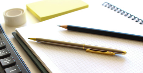 Pen on notebook and calculator isolated on white background