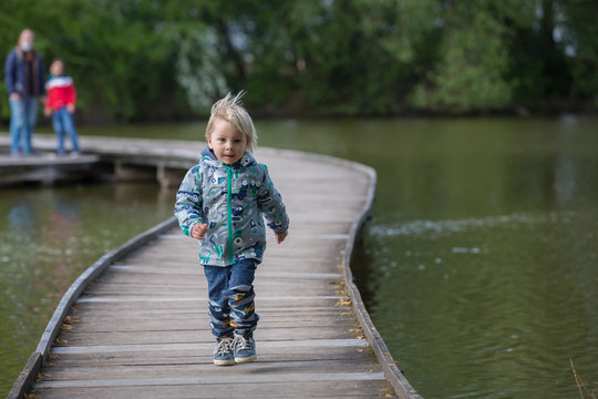 Child, boy, sitting or running on a wooden bridge over lake