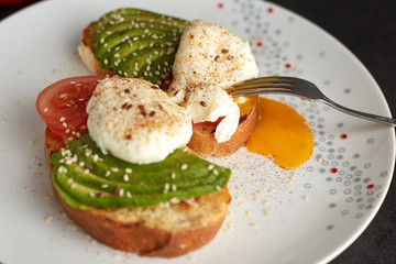 Homemade toast with avocado, eggs, tomato and seeds