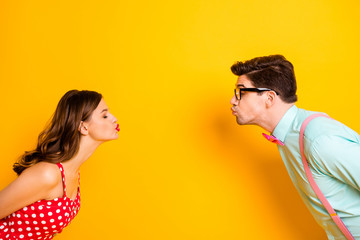 Profile photo of pretty lady handsome guy prom party couple shy kissing first time eyes closed wear red dotted dress shirt bowtie acelegant outfit isolated yellow bright color background