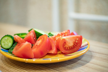 salad of tomatoes and cucumbers in a plate is on a wooden table