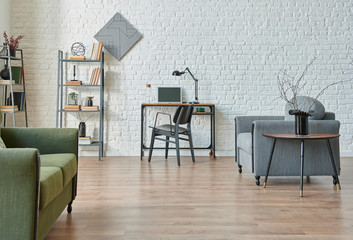 Modern white brick wall background, green and grey sofa, black furniture detail, working table with bookshelf.