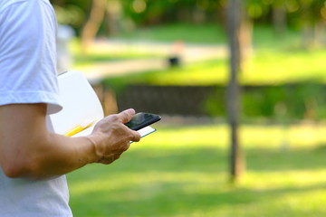 Man using smartphone in the park and checking social networks and reading business news