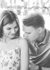 Romantic happy woman and man. Kiss on the shoulder. Young couple walking outdoors in city. Black and white portrait. 