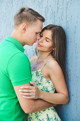 Romantic happy woman and man kissing. Young couple walking outdoors in city. Hug near grey wall.