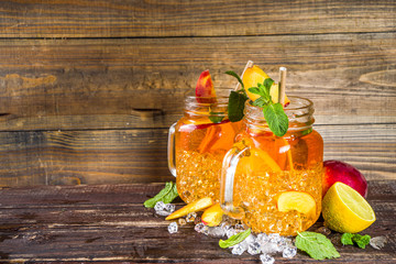Fresh Homemade Peach Sweet Tea with Mint and Lemon Slices, Summer cold fruit drink. Wooden...