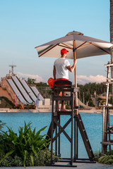 A handsome male lifeguard stands on a tower and looks at the sea. Lifeguards at tropical resorts....
