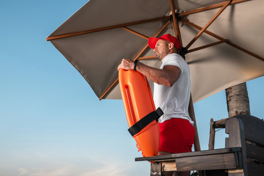 Portrait of a young lifeguard with a rescue orange buoy. Security measures on the beach.