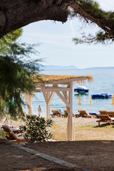Bol on Brac island view with beach beds and sun umbrella’s. A path near the sea on a sunny day in summer in Dalmatia, Croatia. Clear blue Adriatic water at the Mediterranean coast. Idyllic scenery