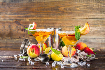 Refreshing summer drink, peach martini cocktails with gin or vodka and fresh peach garnish, wooden...