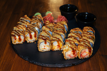 A set of sushi. Philadelphia roll, California, unagi, black dragon with fresh ingredients. The sushi menu. Japanese cuisine. Ginger and wasabi. Soy sauce. Sesame. Hot, baked, breaded