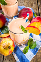 Summer breakfast drink, fresh blended peach smoothie, peach yogurt with nectarine fruit slices, rustic wooden background copy space