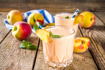 Summer breakfast drink, fresh blended peach smoothie, peach yogurt with nectarine fruit slices, rustic wooden background copy space