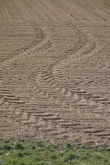Fototapeta na wymiar Traktorspuren im braunen Ackerboden