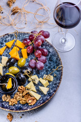 Cheese plate with grapes and olives. Snacks and cheese served with red wine. Top view, copy space.