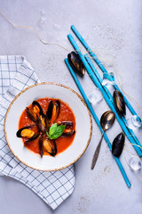 Delicious seafood mussels with tomato sauce and basil. Clams in the shells soup. Top view, copy space