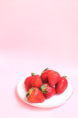 Top view plate of a fresh strawberry on pink background. Summer healthy eating concept.