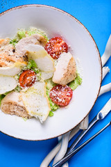 Caesar salad with chicken And cheese in a bowl. Salad with grilled chicken. Chicken breasts and fresh green salad leaves. Top view.
