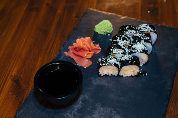 A set of sushi. Philadelphia roll, California, unagi, black dragon with fresh ingredients on a black background. The sushi menu. Japanese cuisine. Ginger and wasabi. Soy sauce. Sesame