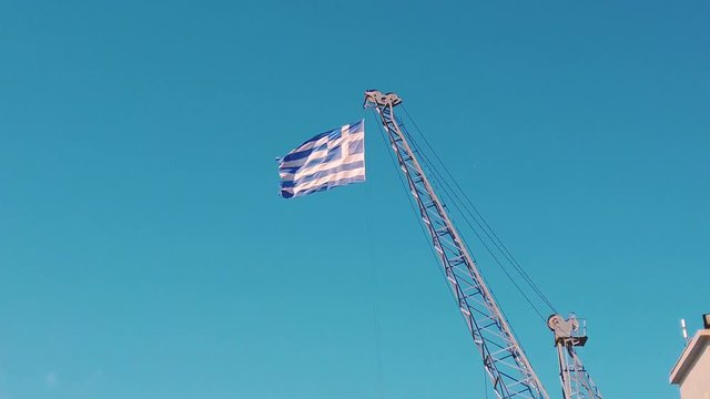 4k clip of the Greek flag waving on the top of a crane in  port of Thessaloniki in Greece with clear sky 