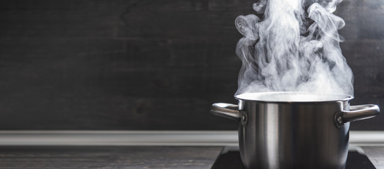 Dense steam coming out the saucepan with freshly cooked food, copy space.