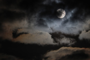 Naklejka na ściany i meble Full moon hidden behind clouds