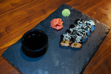 A set of sushi. Philadelphia roll, California, unagi, black dragon with fresh ingredients on a black background. The sushi menu. Japanese cuisine. Ginger and wasabi. Soy sauce. Sesame