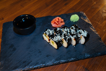 A set of sushi. Philadelphia roll, California, unagi, black dragon with fresh ingredients on a black background. The sushi menu. Japanese cuisine. Ginger and wasabi. Soy sauce