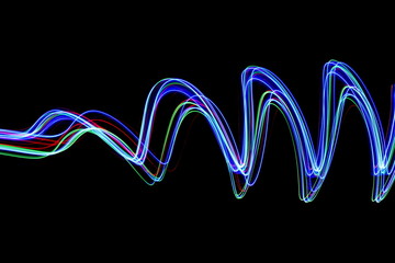 Long exposure photograph of neon multi colour in an abstract swirl, parallel lines pattern against a black background. Light painting photography.