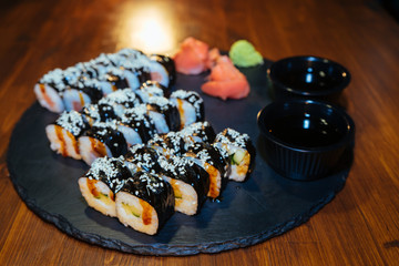 A set of sushi. Philadelphia roll, California, unagi, black dragon with fresh ingredients on a black background. The sushi menu. Japanese cuisine. Ginger and wasabi. Soy sauce