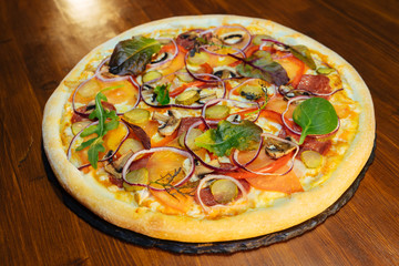Italian pizza with mushrooms and herbs on a wooden table