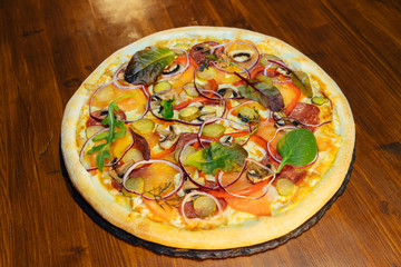 Italian pizza with mushrooms and herbs on a wooden table