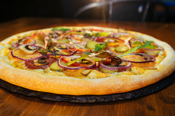 Italian pizza with mushrooms and herbs on a wooden table
