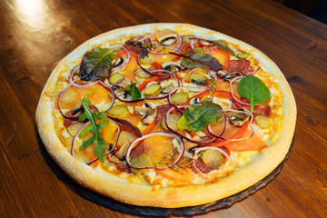 Italian pizza with mushrooms and herbs on a wooden table