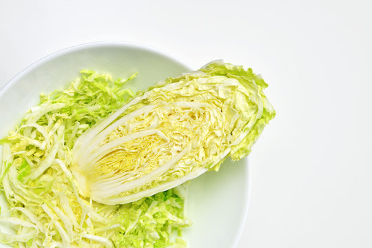 Fresh chinese cabbage salad in bowl on white table background. Vegan food lifestyle. Top view, copy space.
