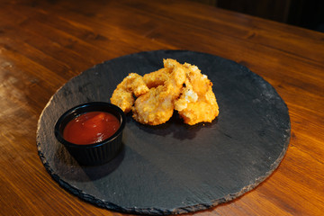 fish or meat in breaded batter with sauce on a tray of slates