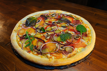 Italian pizza with mushrooms and herbs on a wooden table